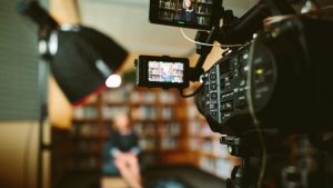 Image of professional camera set up to record a woman sitting in library. 